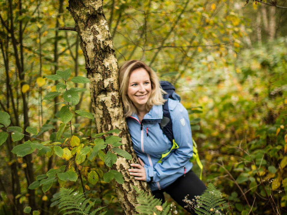 Wanderin lehnt am Baum