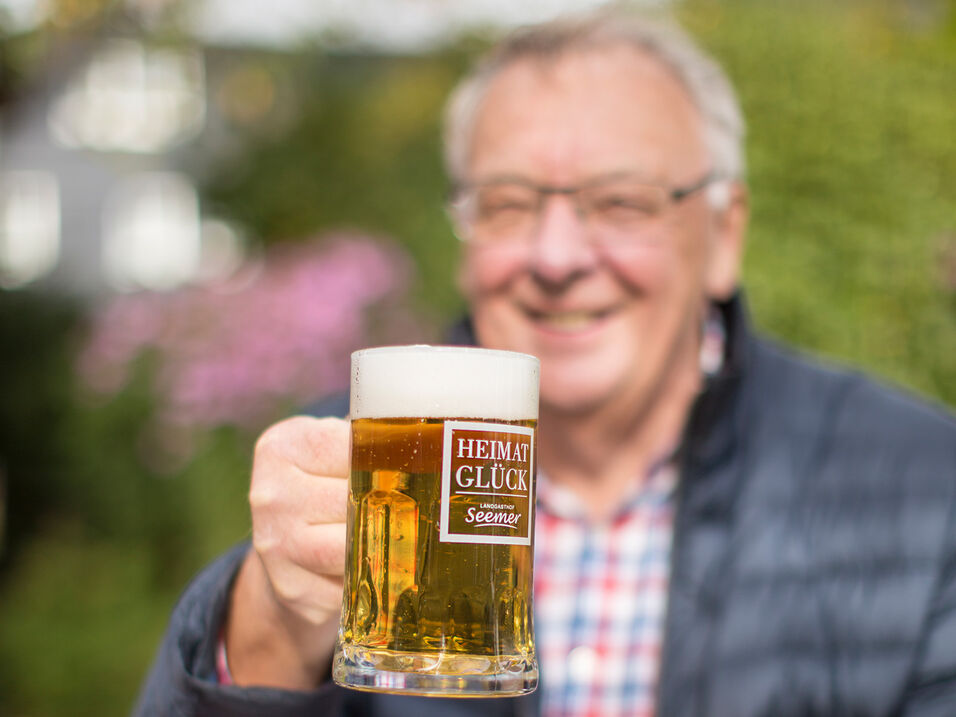 Mann prostet mit dem Bier in die Kamera